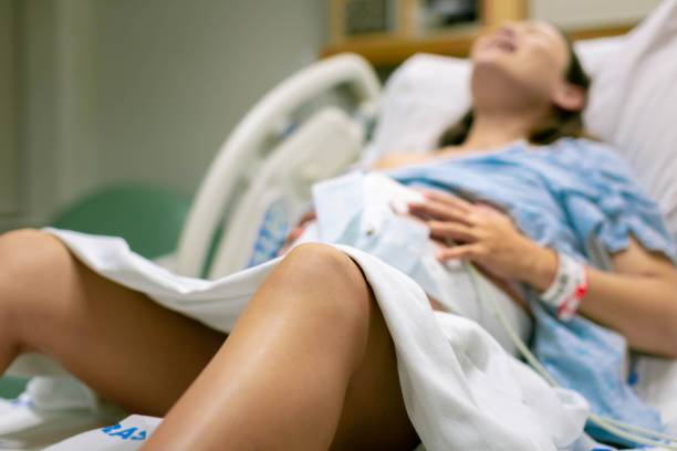A woman in labor, with painful contractions, lying in the hospital bed. Childbirth and baby delivery. stock photo