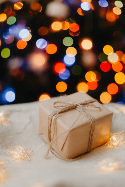 istock small gift laying on white sweater, decorated Christmas tree on background. 1356116359