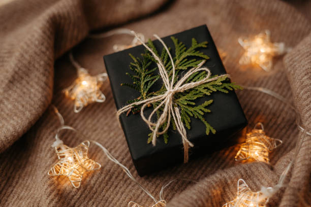 istock Christmas gift packed in black wrapping paper lying on soft woolen background 1356116676