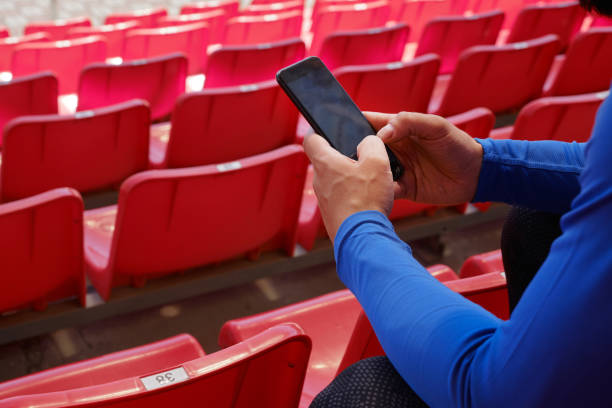 istock Sportsman using phone at the stadium 1356119103