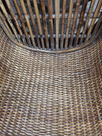 Horizontal shot of dark brown color gradient partial bamboo and cane wicker chair seat woven in a beautiful rustic pattern