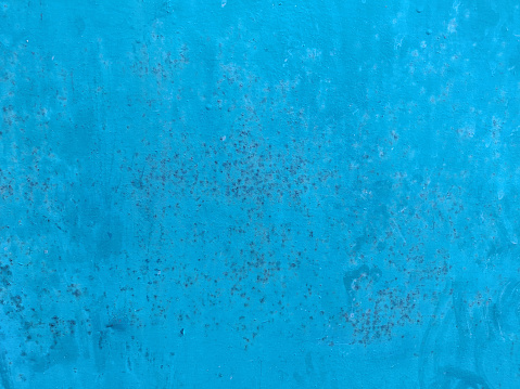An iron metal sheet painted in bright turquoise blue color that is old and rusty and weathered  with no text but brown rust arks or stains all over. Serves as an empty blank rustic backdrop with no text, no people and copy space.
