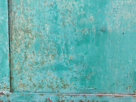 An iron metal sheet with border painted in green color that is old and rusty and weathered  with no text but brown rust arks or stains all over. Serves as an empty blank rustic backdrop with no text, no people and copy space.