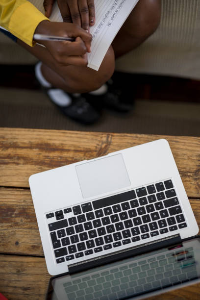 istock Top view laptop and schoolgirls hands writing 1356120506