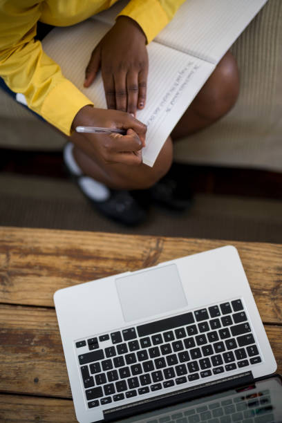 istock Top view laptop and schoolgirl writing in note book 1356120507