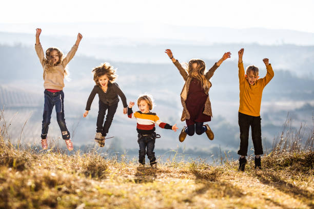 istock Happy kids having fun while jumping and screaming in a meadow. 1356121606