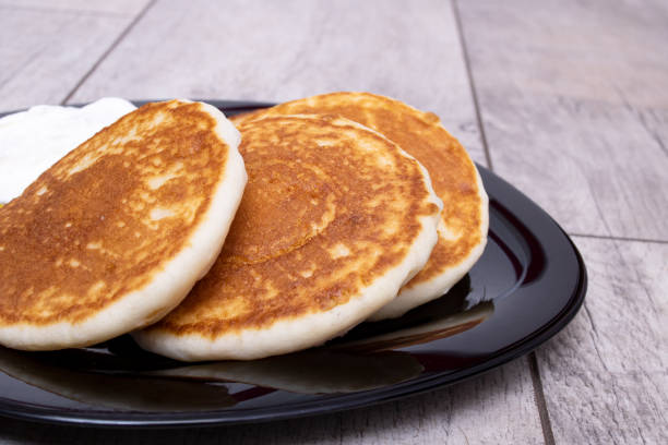 istock Pancakes and sour cream on plate on wooden table 1356122297