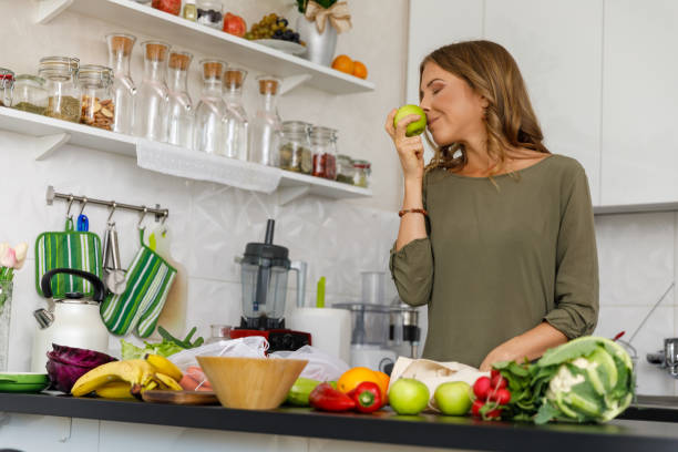 istock Woman smelling a green apple while unpacking groceries 1356123779