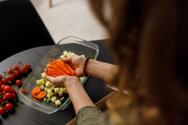 istock Woman arranging carrot sticks she cut up into a glass baking tray 1356123785