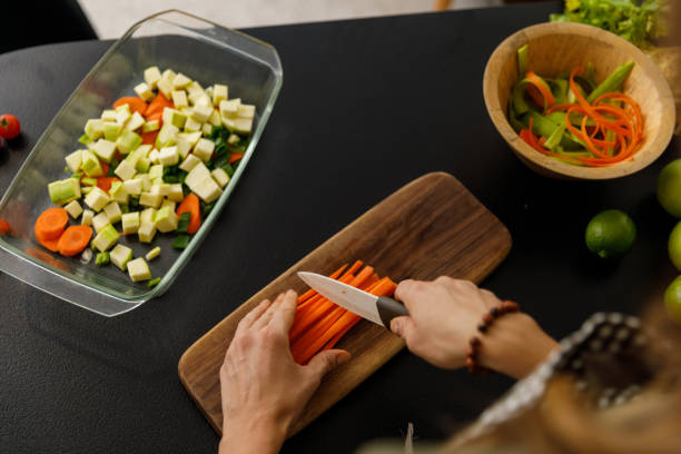 istock Woman cutting up carrot sticks for a healthy dish she is preparing 1356123786