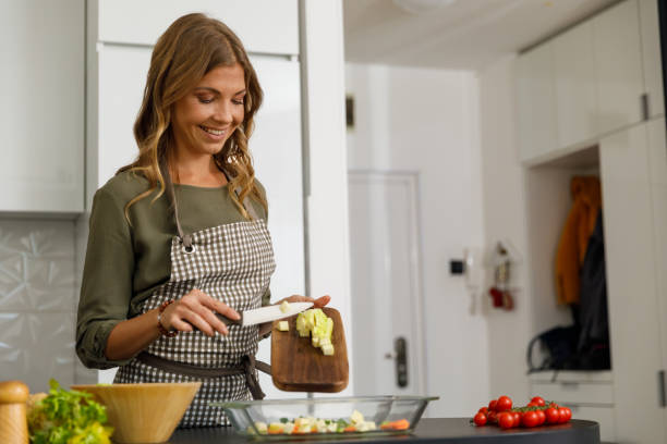 istock Smiling woman transferring chopped zucchini into a glass baking tray 1356123797