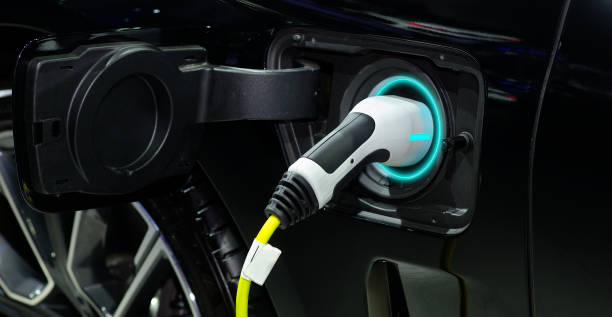 충전식 배터리, 제로 배출 차량(zev) 및 스마트 라이프를 위한 녹색 에너지를 위해 블랙 모던 카의 소켓 충전과 연결된 산업용 전기 충전기의 클로즈업 핸드 그립 플러그 - 하이 앵글 뉴스 사진 이미지