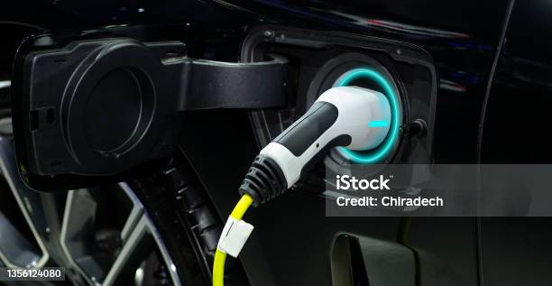 Closeup Hand Grip Plug Of Industrial Electric Charging Machine Connected With Socket Charge On Black Modern Car For Rechargeable Battery Zero Emission Vehicle And Green Energy For Smart Life Stock Photo - Download Image Now