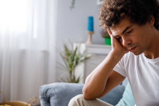istock Distraught young man holding head in hand, looking down 1356124795