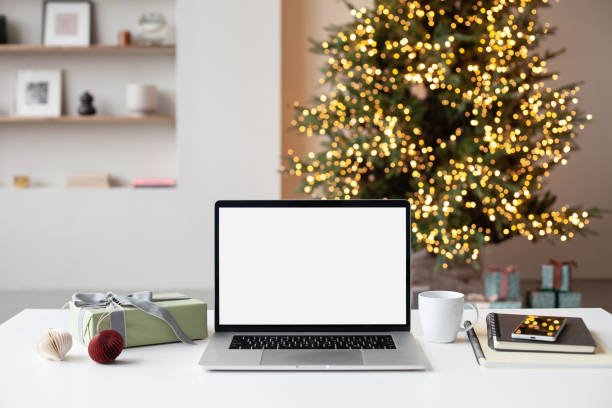 Place of work during Christmas time. Laptop with blank empty screen at home desk stock photo