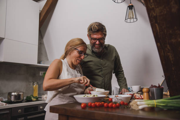 istock Happily married mature couple preparing dinner together 1356125922