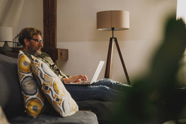 istock Mature man relaxing on the sofa and using laptop 1356125965