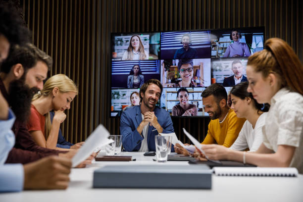 istock Cheerful manager smiling at camera while his employees are reviewing paperwork during a meeting 1356126201