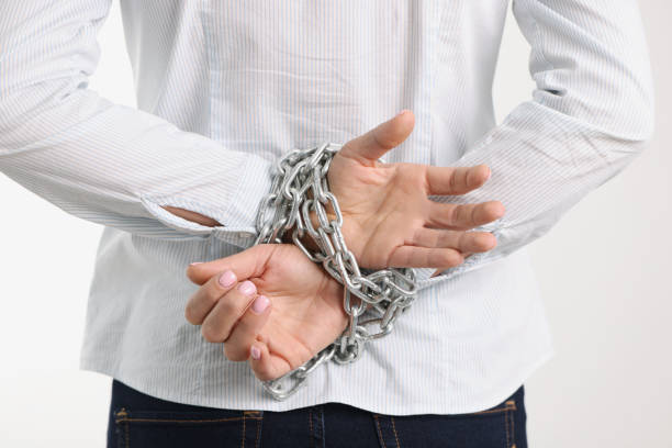 Woman hands are tied with chain behind backs. Not freedom and female slavery concept
