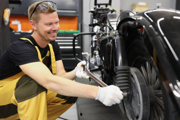 istock Smiling locksmith with wrench near motorcycle wheel in car workshop 1356126227