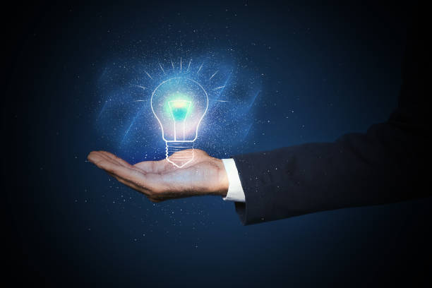 istock Idea concept. Businessman demonstrating glowing light bulb illustration on dark background, closeup 1356126341