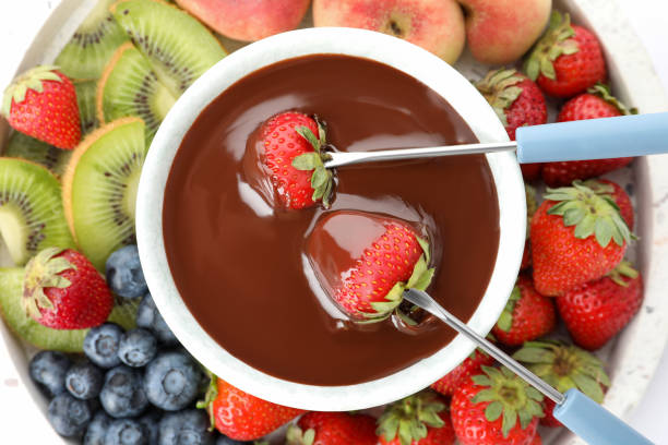 istock Dipping strawberries into fondue pot with chocolate, top view 1356126415