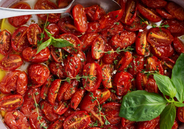 istock Baked cherry tomato with garlic, thyme and basil in old baking pan on concrete vintage background. Top view 1356126677