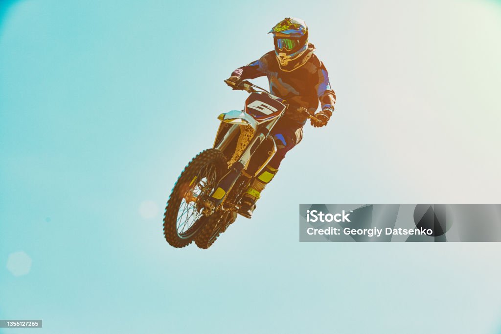 Extreme sports, motorcycle jumping. Motorcyclist makes an extreme jump against the sky. Extreme sports, motorcycle jumping. Motorcyclist makes an extreme jump against the sky. Special processing under the film with flare Motocross Stock Photo