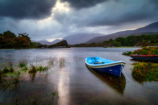 Beautiful scenery of the Killarney lake with boat at dusk, County Kerry Beautiful scenery of the Killarney lake with boat at dusk, County Kerry. Ireland killarney lake stock pictures, royalty-free photos & images