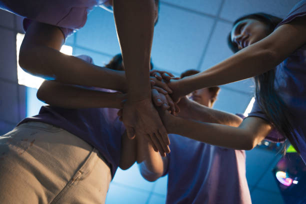 People with stack of hands showing unity and teamwork while celebrating success after game