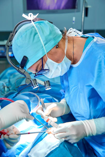 Close-up of an operating surgery team. A team of surgeons professionals with assistants in the operating room. Blue medical light. Surgery, saving lives, modern equipment stock photo