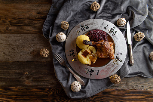 Traditional german christmas meal. Served with potato dumplings, red cabbage and roasted duck with gravy. Served on rustic and wooden table. Overhead view with copy space