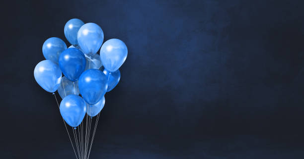 Blue balloons bunch on a black wall background. Horizontal banner. stock photo