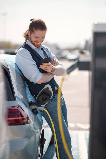 istock man using smartphone near electric car on charging station 1356134991