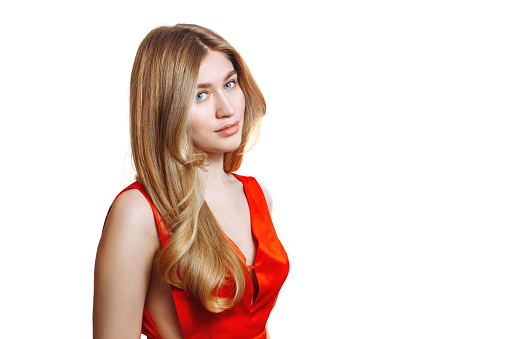 Portrait of a girl with beautiful long blond hair on a white isolated background in a red dress