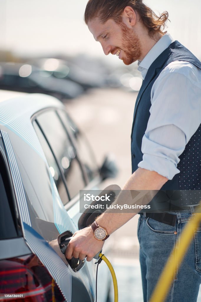 man charging his non-polluting electric vehicle young man charging his non-polluting electric vehicle Car Stock Photo