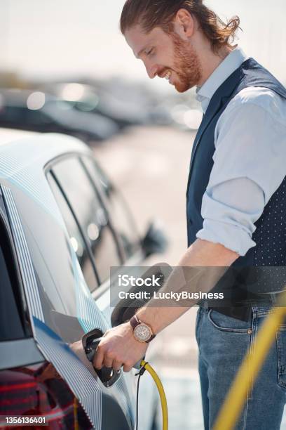 Man Charging His Nonpolluting Electric Vehicle Stock Photo - Download Image Now - Car, Electro Music, Electronics Industry