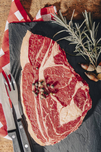 istock raw steak on pizarra dish isolated on black background. 1356137871