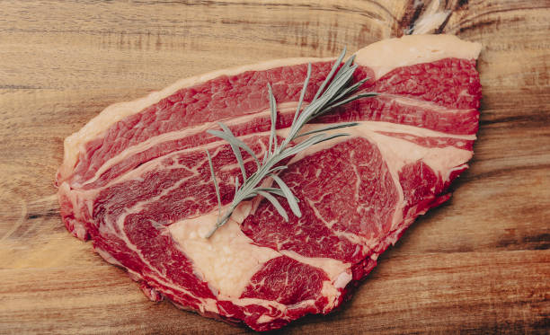 istock raw steak on pizarra dish isolated on black background. 1356137916
