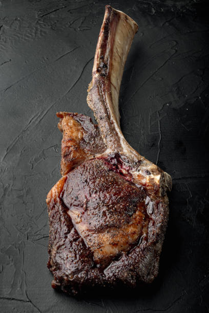 istock Juicy steak grilled on the bone tomahawk marbled beef, on black stone background 1356138691