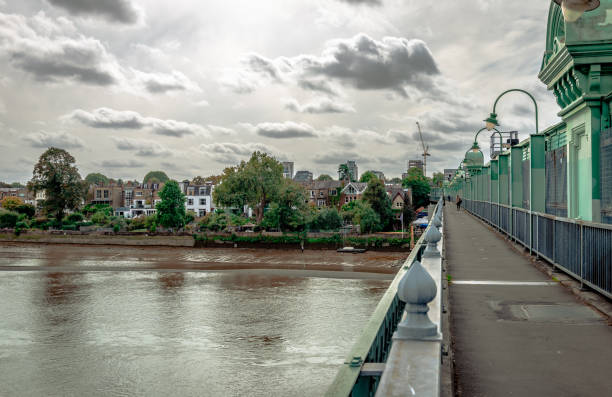 The Fulham Railway Bridge over the river Thames with Putney in the background. London, UK. The Fulham Railway Bridge that spans the river Thames, seen from the north. Colloquially known as The Iron Bridge, it can also be crossed on foot. Putney is in the background. putney photos stock pictures, royalty-free photos & images