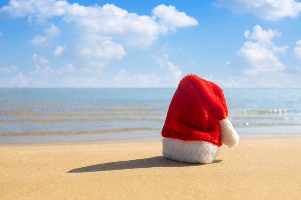 istock Santa hat on sandy beach. Concept of celebrating new year 1356139089