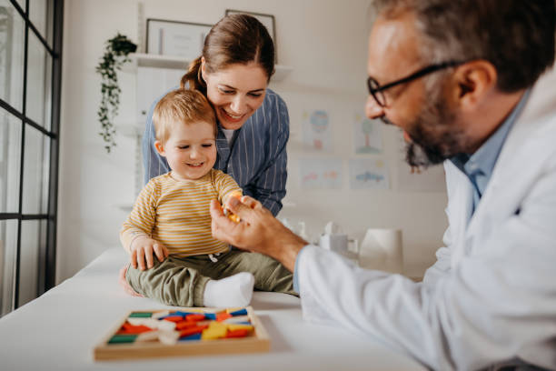 medico e madre che giocano con il bambino - healthcare and medicine smiling group of people lab coat foto e immagini stock