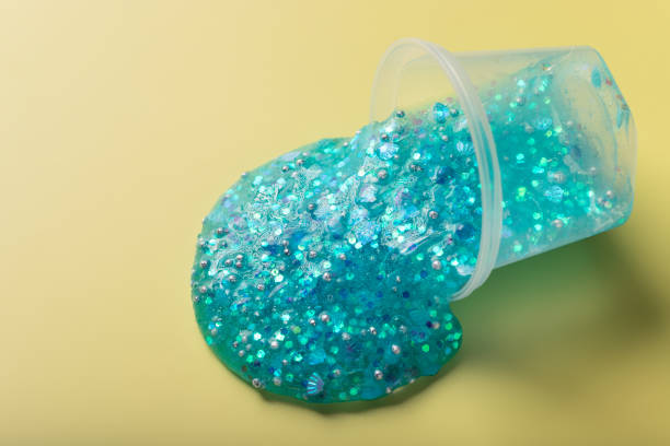 istock Flowing blue slime with glitter on yellow background 1356141247