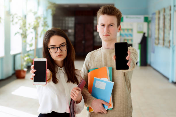 Student showing screens of their phones Bored student receive notification with bad information showing screens of their phones to the camera looking distracted and unhappy male college student sleeping through lecture stock pictures, royalty-free photos & images