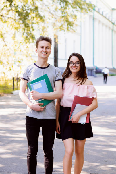 education, campus, friendship and people concept - group of happy teenage students with school folders