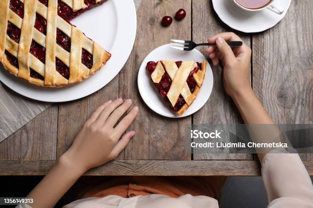 Woman Eating Delicious Cherry Pie At Wooden Table Top View Stock Photo - Download Image Now