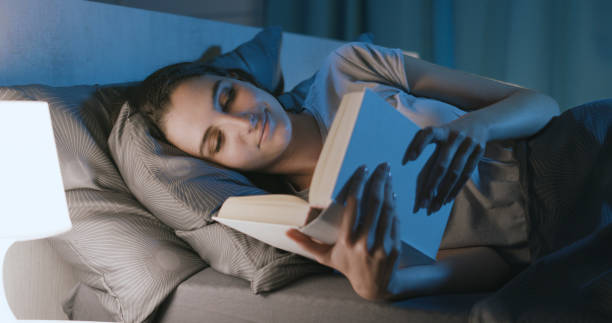 istock Woman lying in bed and reading a book 1356150233