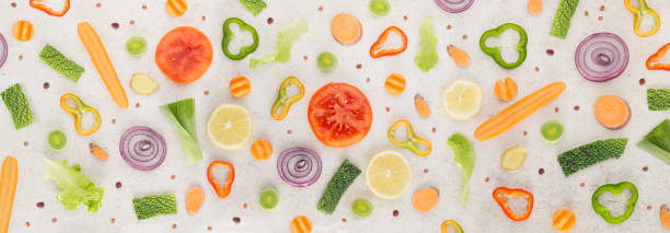 Lemon slices, green pepper, red onion, tomatoes, lettuce, leek, carrot, sweet potato, ginger and kale on marble background. Colorful vegetable natural healthy food pattern. Raw concept. Top view.