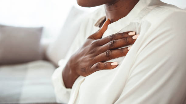 fille ayant des problèmes de respiration touchant la poitrine assise sur un canapé dans le salon à la maison. - asthmatic photos et images de collection